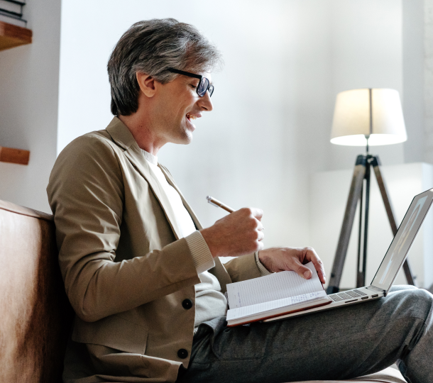 A man seated on a couch, focused on his laptop, creating a relaxed yet productive atmosphere in his living space.