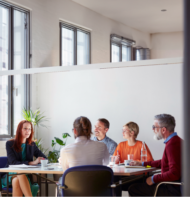 A diverse group of individuals engaged in conversation while seated around a table in a collaborative setting.