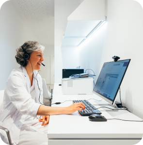 A woman with a headset is seated at a desk, focused on her computer screen, engaged in her work.