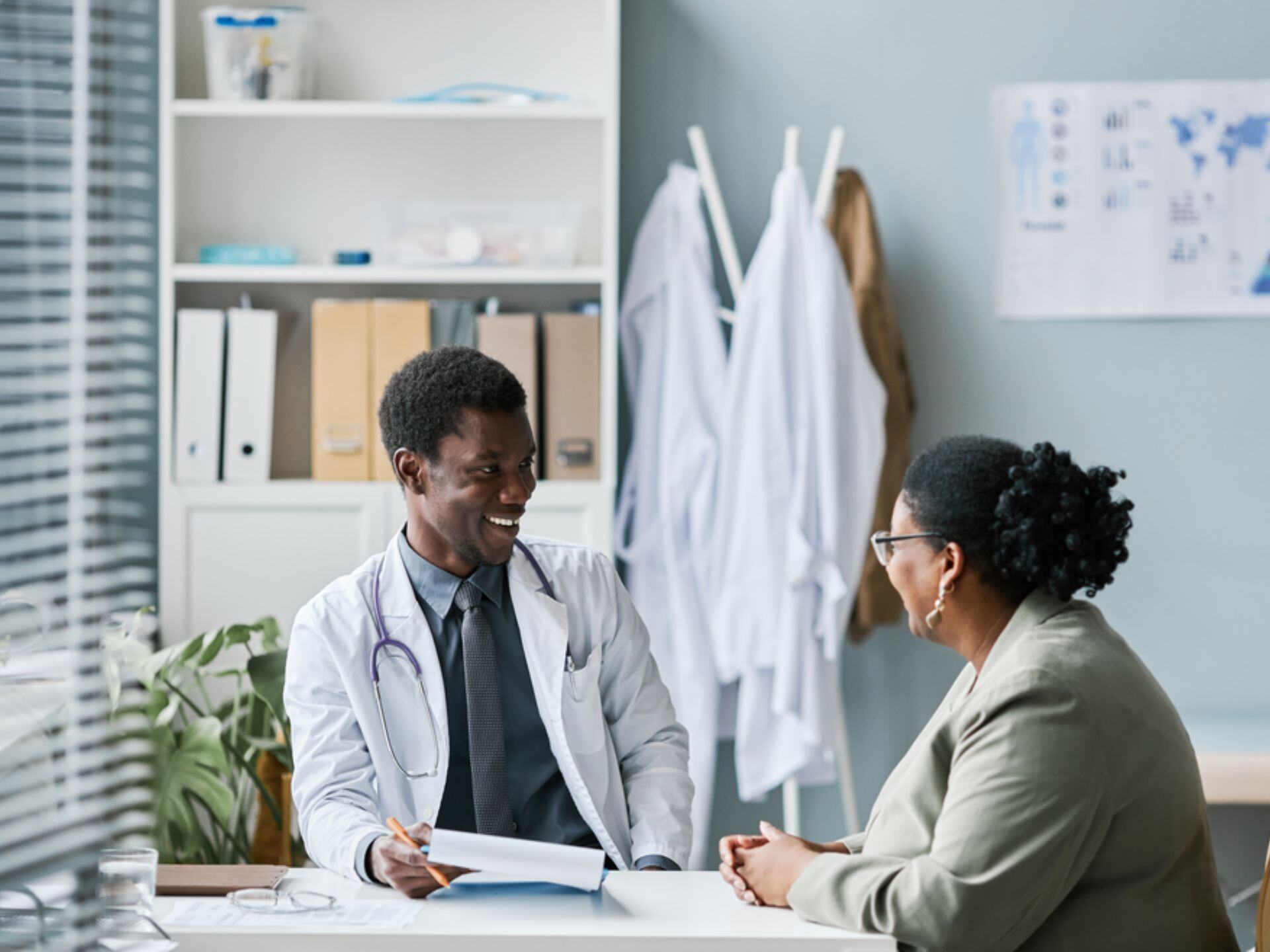 Young doctor consulting patient in clinic smiling happily